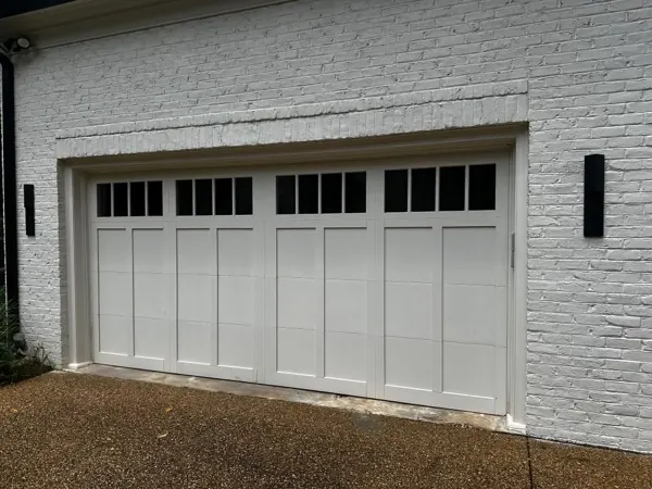 White carriage-house garage door with windows on a painted brick home