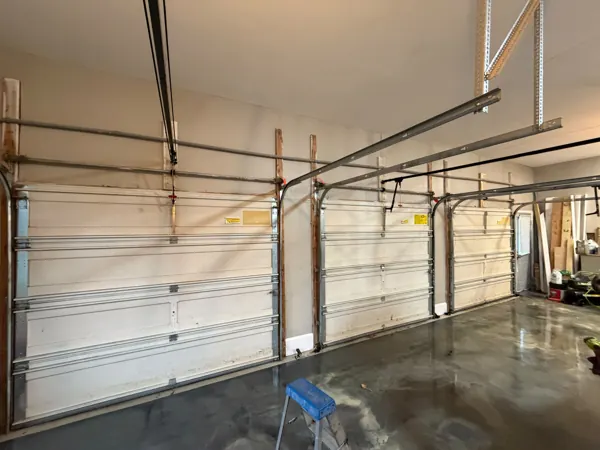 Inside a three-car garage with old reinforced garage doors before replacement