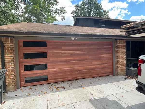 Newly installed modern wood-look garage door with glass windows
