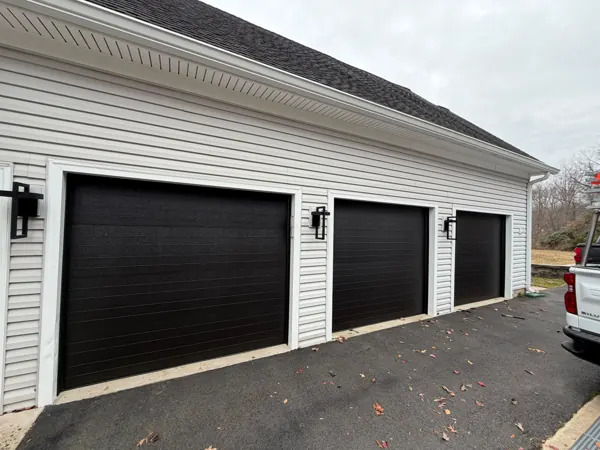 Three new modern black flush garage doors after replacement