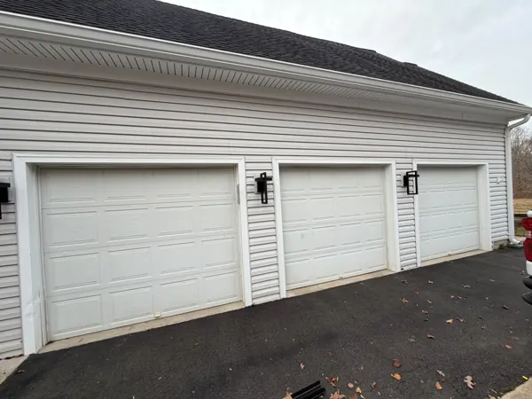 Three white raised-panel garage doors before replacement